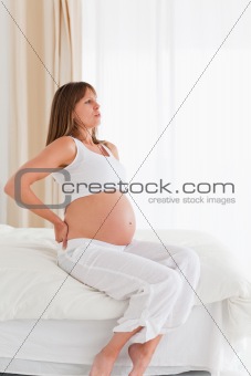 Good looking pregnant female having a back pain while sitting on