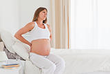 Attractive pregnant female having a back pain while sitting on a