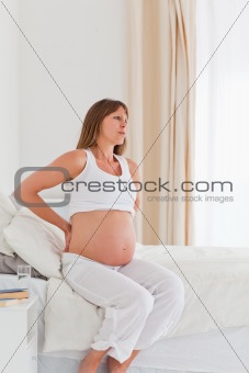 Charming pregnant female having a back pain while sitting on a b