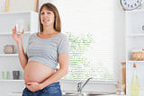 Beautiful pregnant woman holding a glass of water while standing
