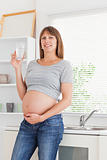 Attractive pregnant woman holding a glass of water while standin