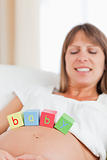 Attractive pregnant woman playing with wooden blocks while lying