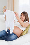 Attractive pregnant woman holding a baby grow while lying on a s