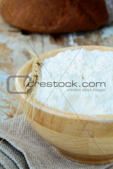 white flour in a wooden bowl with the wheat spikelet