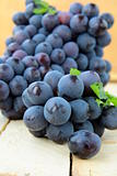 Brush black sweet grapes in a basket on wooden table