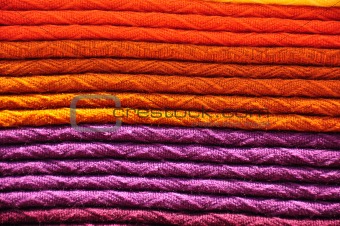 Stack of traditional woven alpaca blankets in orange and purple