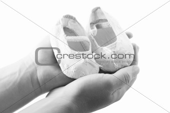 Hands holding newborn baby shoes