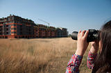 Woman watching with binoculars building construction