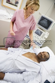 Nurse Checking On Patient Lying On Hospital Bed