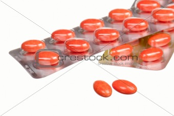 close up orange capsules and blisters isolated on white