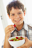 Young Boy Eating Bowl Of Fresh Fruit
