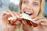 Mid Adult Woman Eating Bacon Sandwich