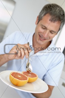 Middle Aged Man Eating Fresh Grapefruit
