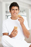 Young Man Eating A Brown Bread Roll