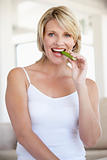 Mid Adult Woman Smiling At Camera And Eating Celery Stick