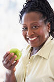 Senior Woman Eating Green Apple And Smiling At The Camera
