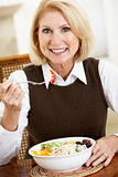 Senior Woman Eating Dinner, Smiling At The Camera