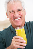 Senior Man Holding A Glass Of Fresh Orange Juice, Smiling At The