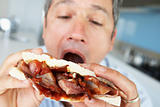 Middle Aged Man Eating A Bacon Sandwich