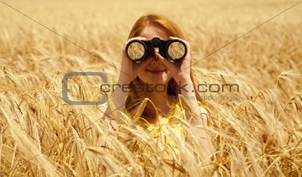 Redhead girl with binocular at wheat field. 