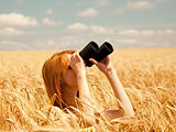 Redhead girl with binocular at wheat field. 