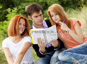 Three students at outdoor doing homework.