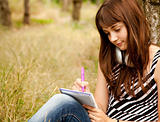 Young teen girl doing homework at the park.