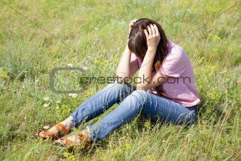 Sad girl at green grass at countryside.