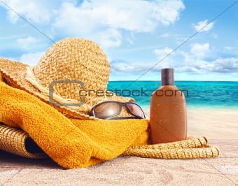 Suntan lotion, straw hat at the beach