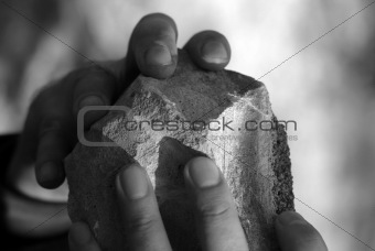the hands of a man with a stone