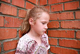 sad child with a brick wall