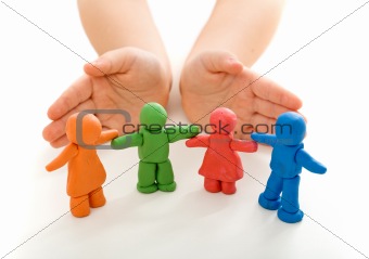 Child hands protecting clay people