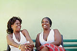 black women with white dress laughing on bench