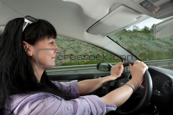 Beautiful young woman drives a car on a highway