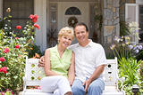 Couple Sitting On Bench Outside House
