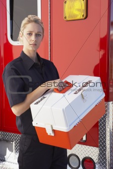Paramedic standing by ambulance with medical kit