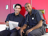 Two paramedics cheerfully doing paperwork, sitting by their ambu
