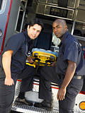 Two paramedics cheerfully removing empty gurney from ambulance