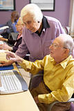 Senior woman helping senior man use computer