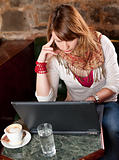 Morning coffee in internet cafe - Beautiful young girl checking news on web and drinking coffe