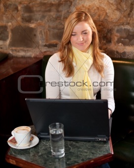 Morning coffee in internet cafe - Beautiful young girl checking news on web and drinking coffe