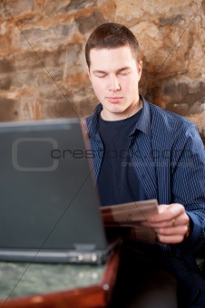 Young man checking mail and drinking coffee in cafe