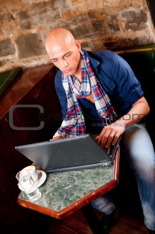 Young man checking mail and drinking coffee in cafe