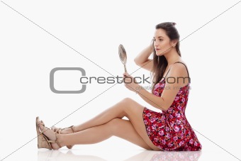woman in summer dress looking at hand mirror - isolated on white