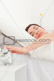 Portrait of a brunette turning off her alarm clock