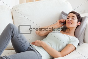 Close up of a brunette calling while lying on a sofa