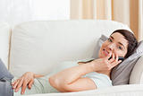 Close up of a calm brunette making a phone call while lying on a