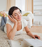 Portrait of a delighted woman with a magazine enjoying some musi