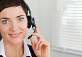 Close up of a smiling secretary calling with a headset