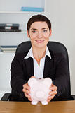 Portrait of a smilling office worker holding a piggybank